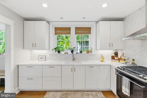 a kitchen with stainless steel appliances granite countertop a sink a stove a refrigerator and a window
