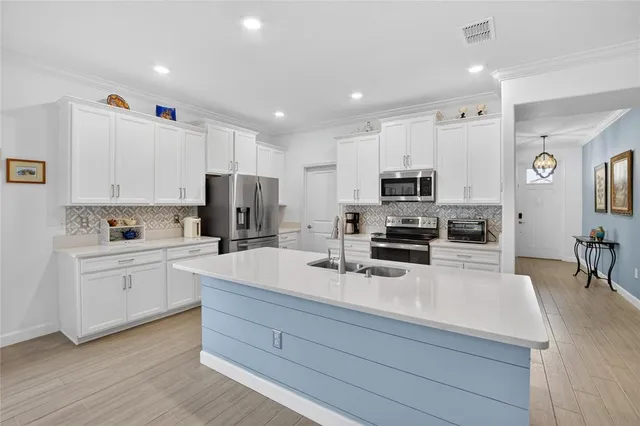 a kitchen with a sink a stove a refrigerator and white cabinets