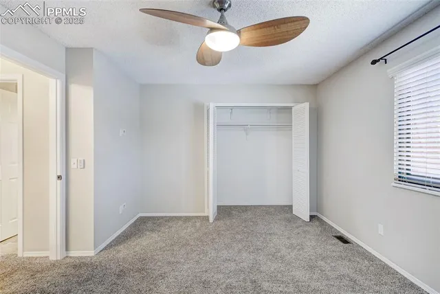 an empty room with closet and a chandelier fan