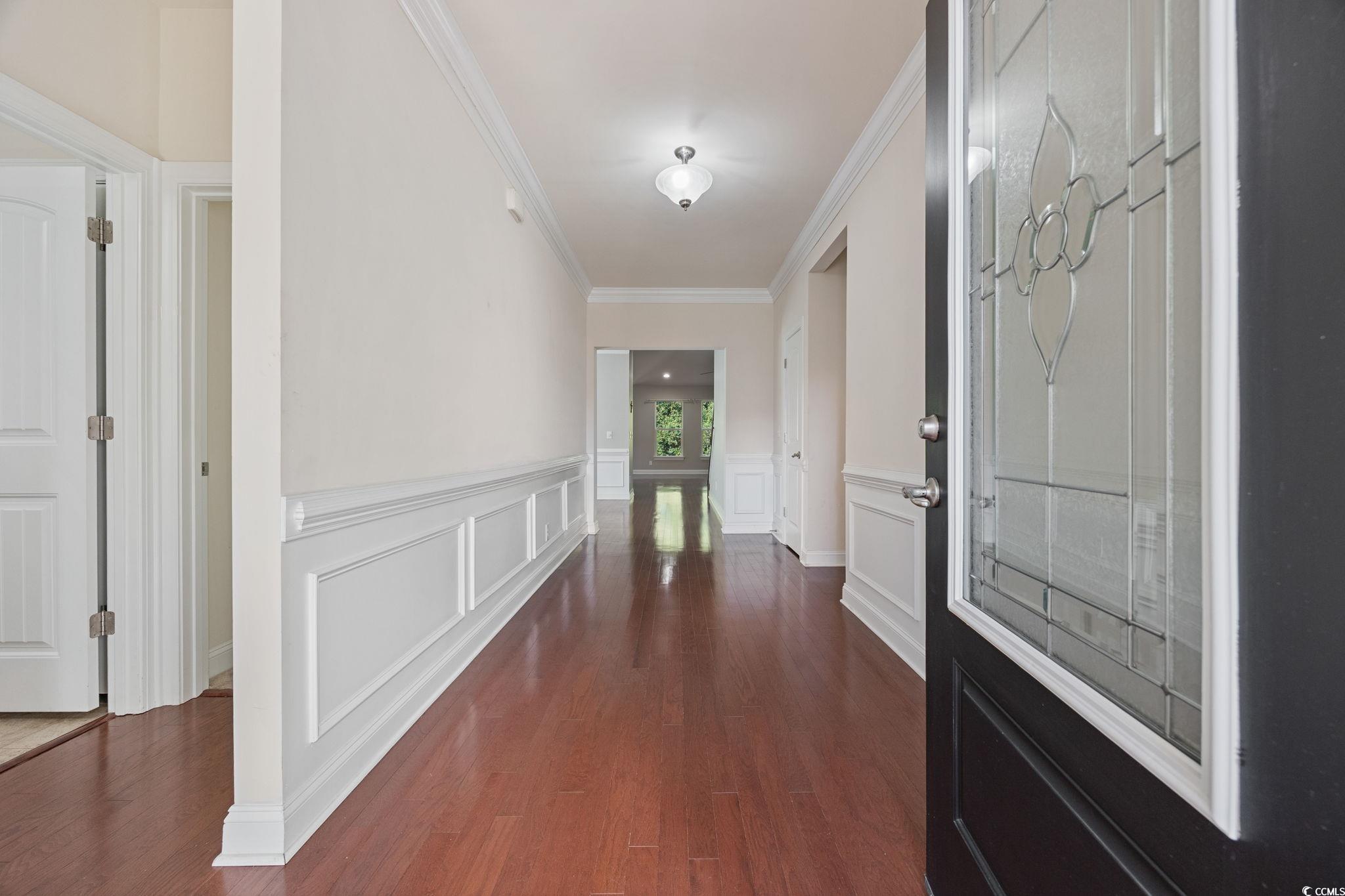 1900 Bluff Drive Myrtle Beach, SC 29577 - Photo 2 of 38 Corridor featuring dark wood finished floors, crown molding, a decorative wall, and wainscoting