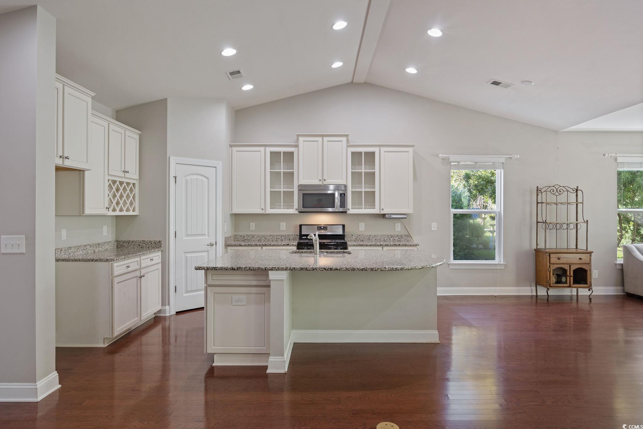 1900 Bluff Drive Myrtle Beach, SC 29577 - Photo 4 of 38 Kitchen featuring light stone counters, white cabinetry, stainless steel appliances, dark wood finished floors, and lofted ceiling