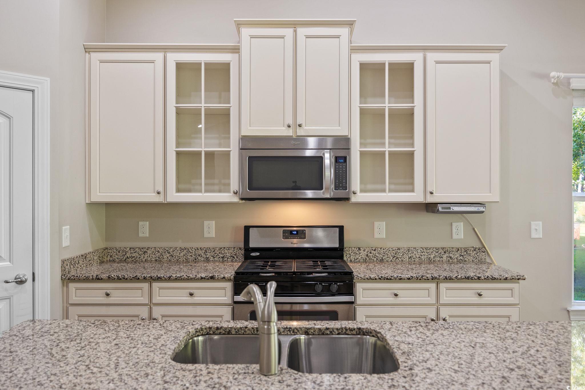 1900 Bluff Drive Myrtle Beach, SC 29577 - Photo 5 of 38 Kitchen featuring stainless steel appliances, light stone countertops, glass insert cabinets, and white cabinets