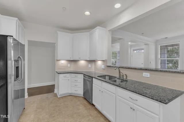 a kitchen with granite countertop white cabinets and stainless steel appliances