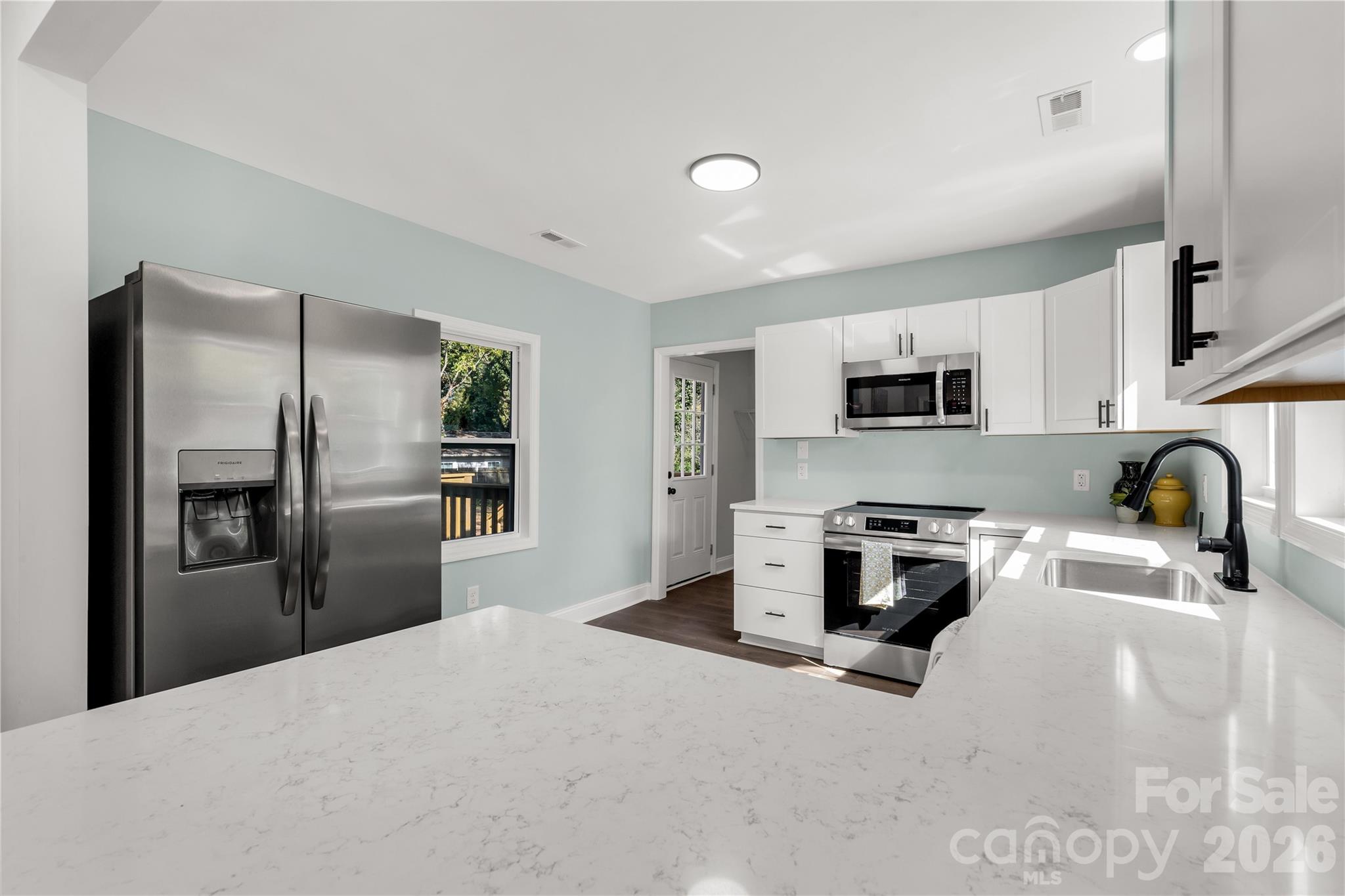 a kitchen with stainless steel appliances granite countertop a refrigerator a stove top oven a sink dishwasher and wooden floor