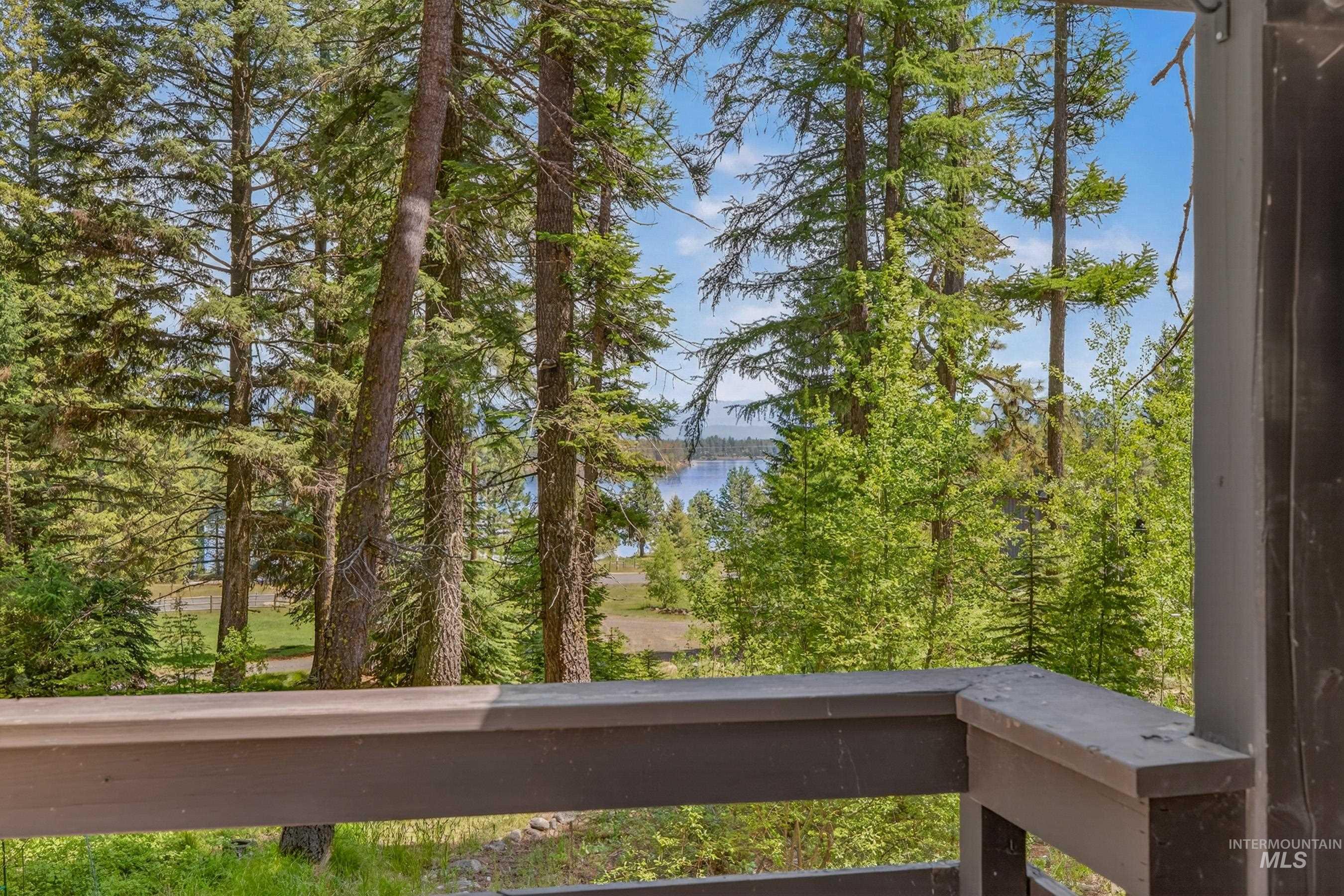 2339 West Mountain Road Donnelly, ID 83615 - Photo 19 of 37 Expansive natural landscape featuring dense evergreen trees, distant water body, and a partial wood-finish railing