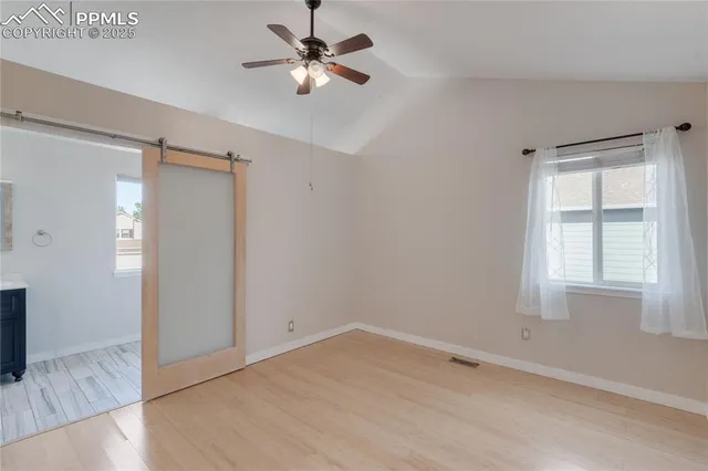 a view of empty room with wooden floor and fan