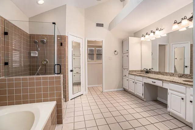 a bathroom with a granite countertop sink a mirror a bathtub and shower