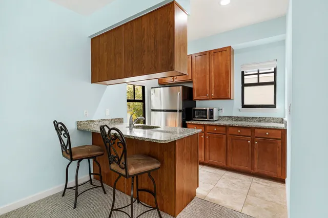 a kitchen with stainless steel appliances granite countertop a table chairs in it and wooden floors
