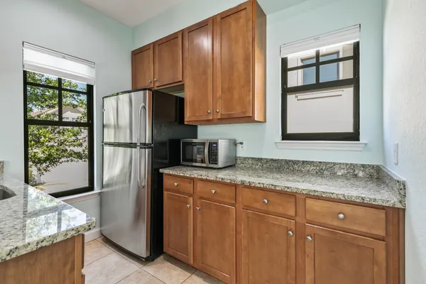 a kitchen with granite countertop wooden cabinets and a refrigerator