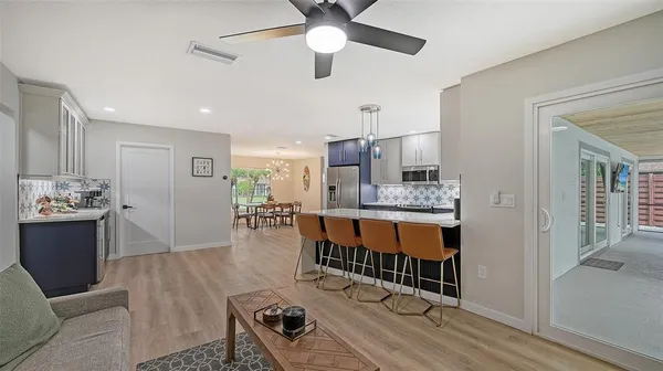 a living room with stainless steel appliances kitchen island granite countertop furniture and a wooden floor