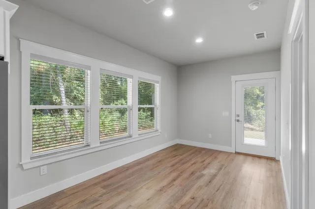 a view of an empty room with wooden floor kitchen appliances and a window