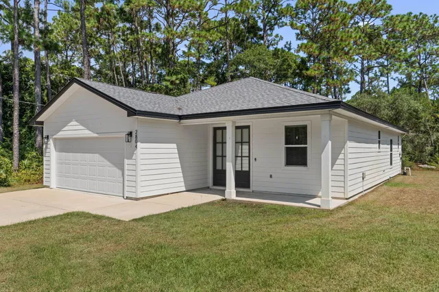 a view of a white house with a yard and garage