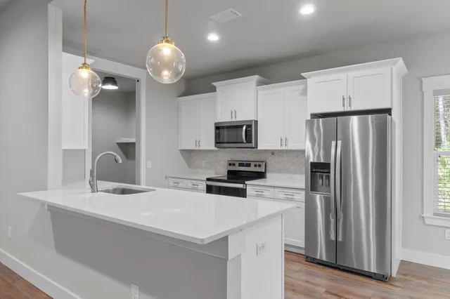 a kitchen with a sink dishwasher and white cabinets with wooden floor