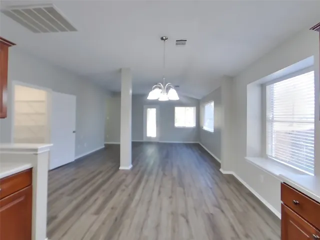 a view of a room with wooden floor chandelier and windows