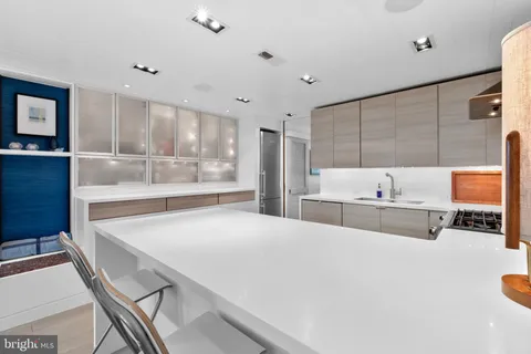 a kitchen with stainless steel appliances a sink a stove a refrigerator cabinets and living room view