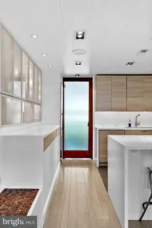 a living room with stainless steel appliances furniture a large window and a refrigerator