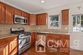 39 Morningside Road Colonia, NJ 07067 - Photo 28 of 30 a kitchen with stainless steel appliances granite countertop a stove top oven a sink with wooden cabinets and entryway