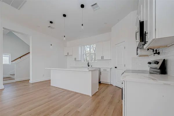 a large kitchen with cabinets wooden floor and stainless steel appliances
