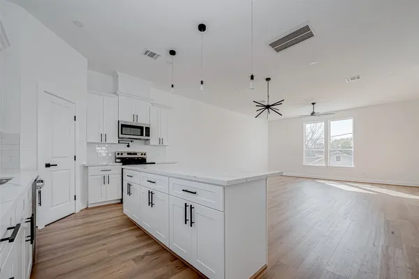 a kitchen with white cabinets stainless steel appliances and wooden floor