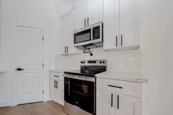 a kitchen with cabinets stainless steel appliances and wooden floor