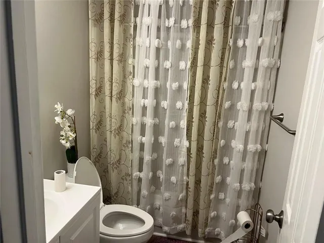 a bathroom with a toilet and shower curtain