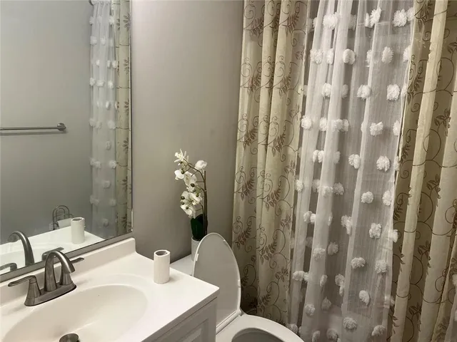 a bathroom with a sink a toilet and shower curtain