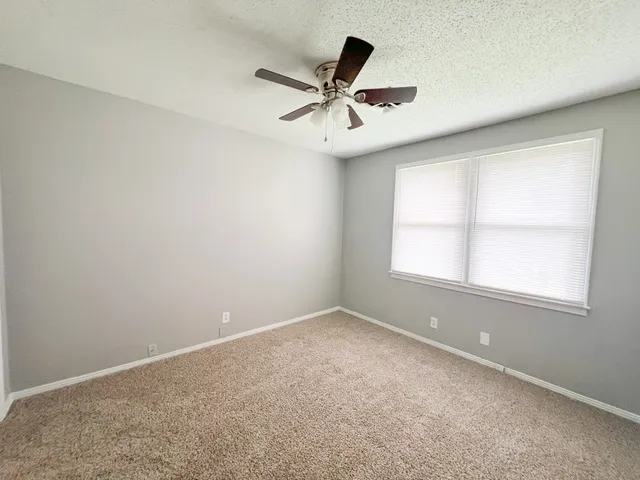 an empty room with a window and a ceiling fan