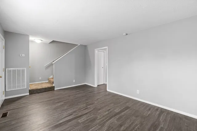 a view of an empty room with wooden floor and stairs