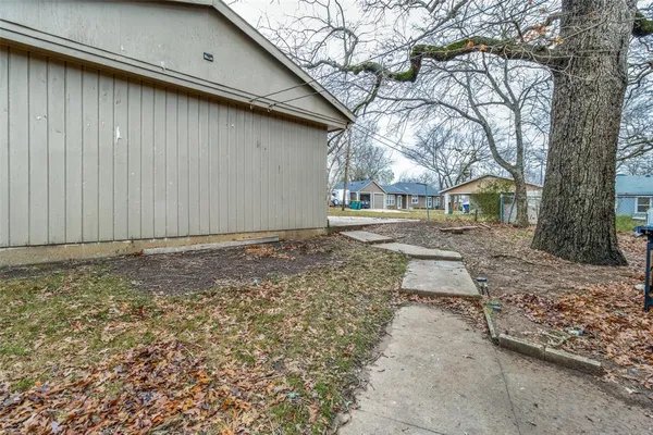 a backyard of a house with large trees and wooden fence