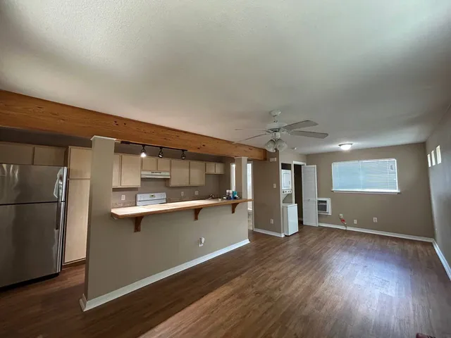 a kitchen with stainless steel appliances granite countertop a refrigerator a sink dishwasher a stove and white countertops with wooden floor