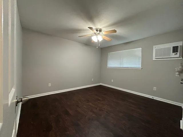 an empty room with wooden floor fan and windows