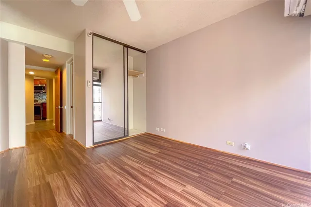 a view of an empty room with wooden floor and a bathroom