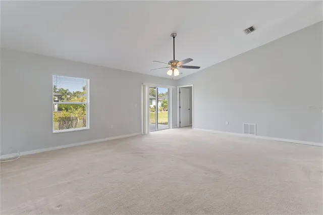 a view of an empty room with window and chandelier fan