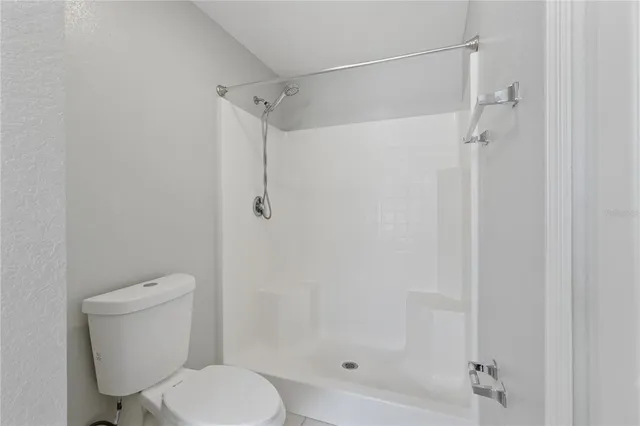 a white toilet next to a bathroom