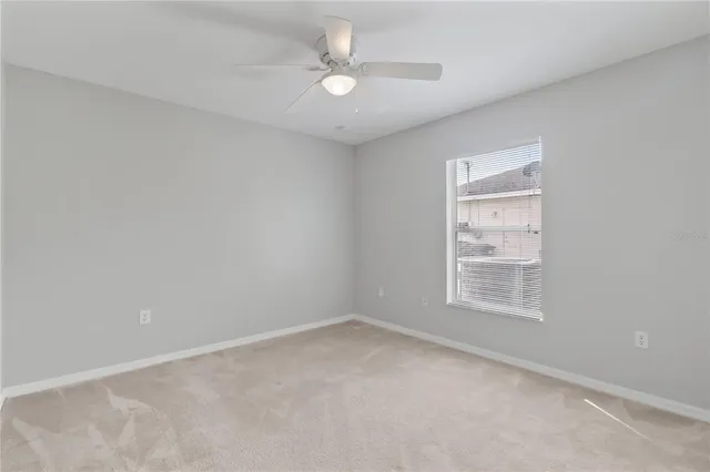 an empty room with a window and a ceiling fan