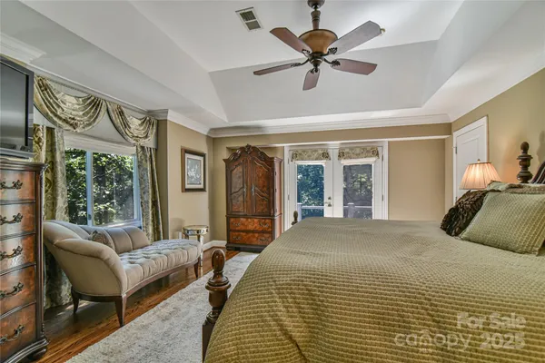 a bedroom with a large bed couch and windows