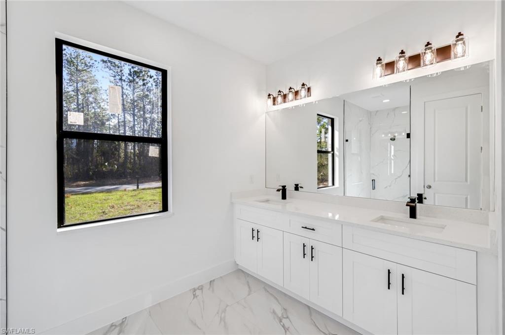 2113 Grayson Avenue Alva, FL 33920 - Photo 13 of 25 Bathroom with double vanity, light marble finish floors, and a marble finish shower