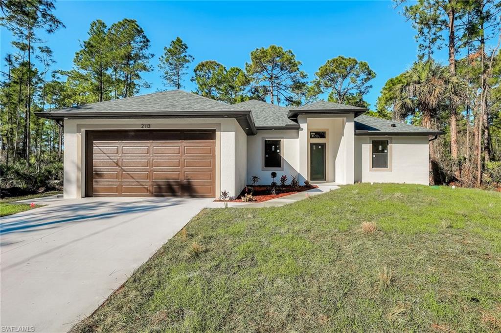 2113 Grayson Avenue Alva, FL 33920 - Photo 2 of 25 View of front of property featuring a front yard, stucco siding, driveway, a garage, and a shingled roof