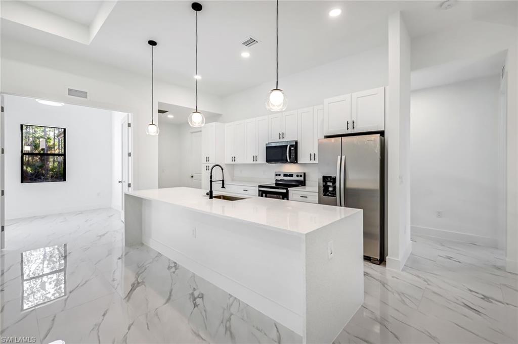 2113 Grayson Avenue Alva, FL 33920 - Photo 9 of 25 Kitchen featuring light stone counters, stainless steel appliances, pendant lighting, white cabinetry, and a center island with sink