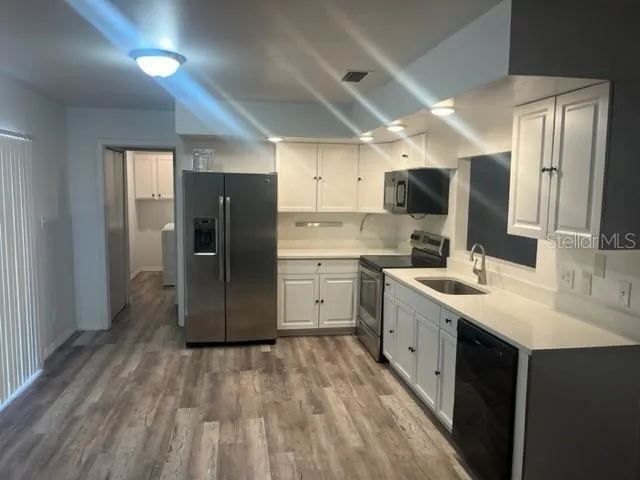 a large kitchen with a sink refrigerator and microwave