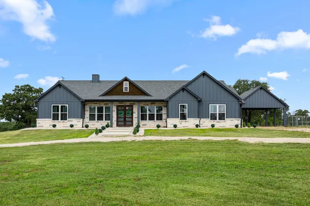 a front view of a house with a garden and trees