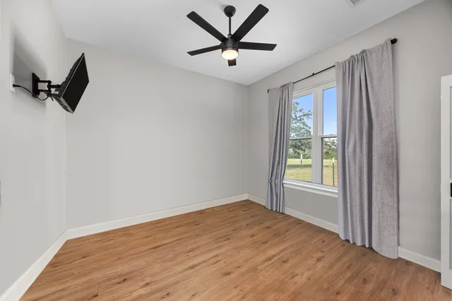 an empty room with a window and a ceiling fan