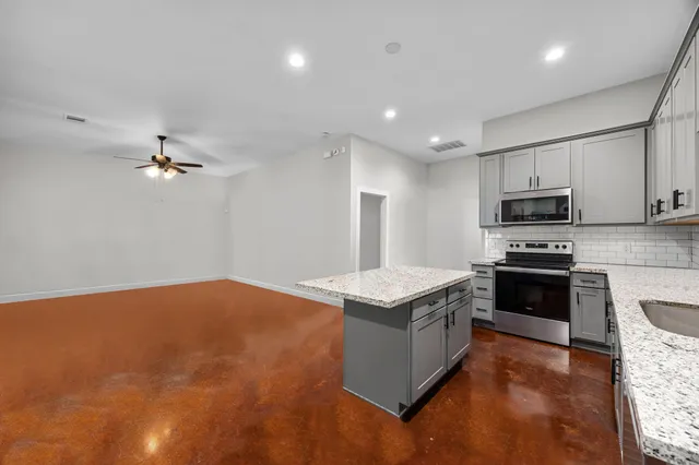 a kitchen with kitchen island a stove a sink and a microwave