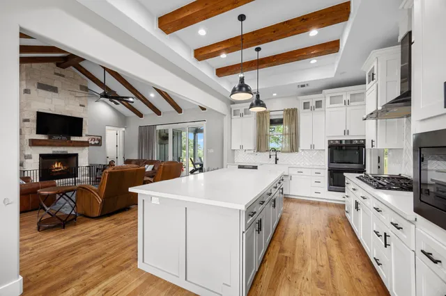 a large white kitchen with stainless steel appliances granite countertop a stove and a wooden floors