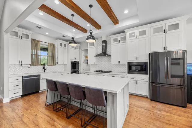 a kitchen with granite countertop a refrigerator a stove a sink dishwasher a dining table and chairs with wooden floor