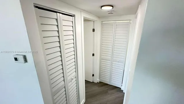 a view of a hallway with wooden floor and closet