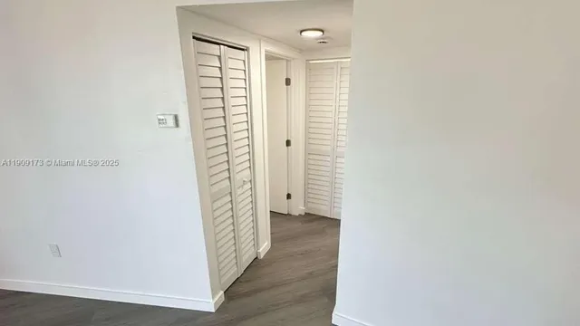 a view of a hallway with wooden floor and closet