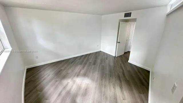 an empty room with wooden floor and a window