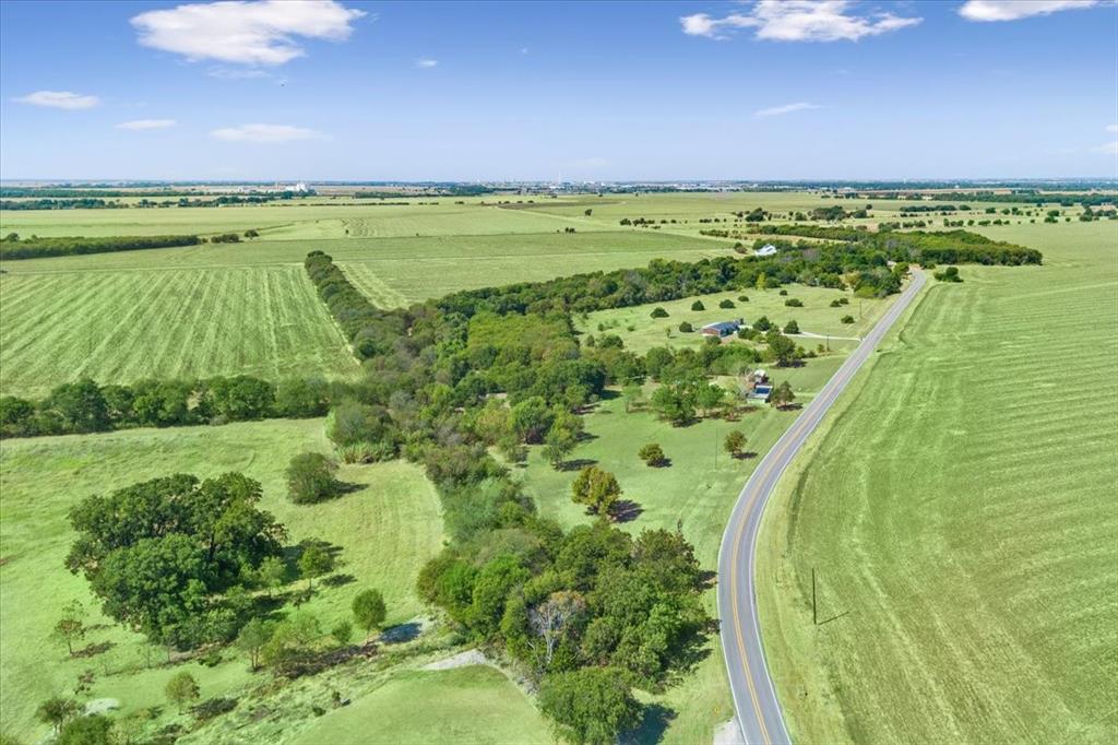 4246 Old Caufield Ranch Road McGregor, TX 76657 - Photo 26 of 31 Expansive green fields, a paved road, scattered mature trees, and a distant treeline