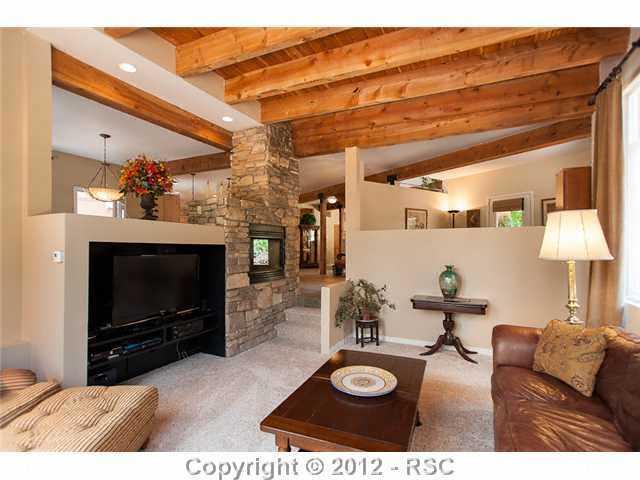 5610 Timpa Road Cascade, CO 80809 - Photo 5 of 16 The living room is open to the den on one side and dining room on the other and features a multi media center and double sided gas fireplace